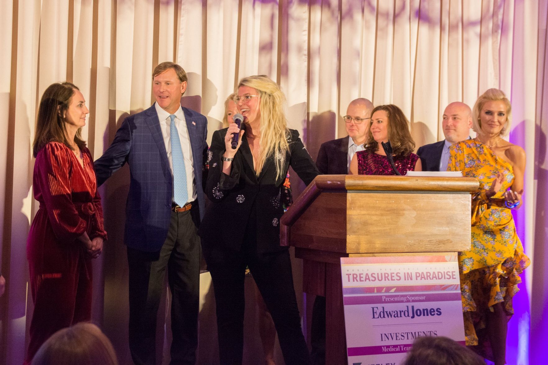 Kim Cella gives the introduction to the event among other speakers and co-chairs on stage at Treasures in Paradise